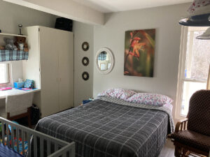 Image of a bedroom with a crip and a desk